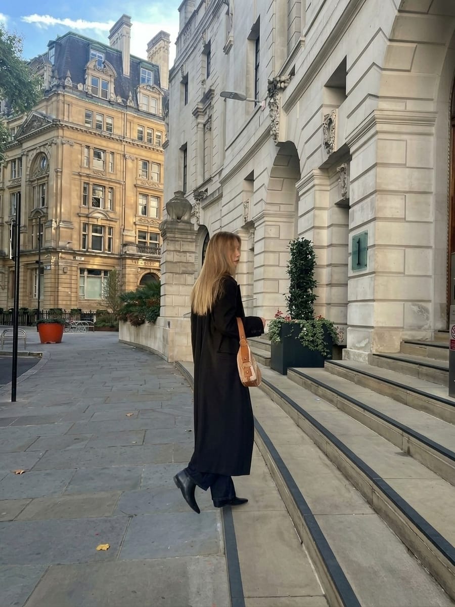 A member in a long dark coat arriving at a stone building on Finsbury Circus, City of London.