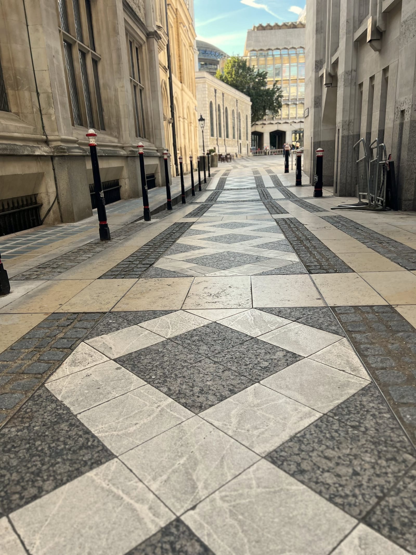 A quiet paved approach to Guildhall, lined with black and red bollards